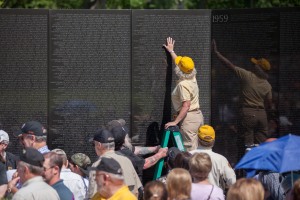 Wall Volunteer Annmarie touches The Wall before she makes a name rubbing during Memorial Day weekend, 2014.